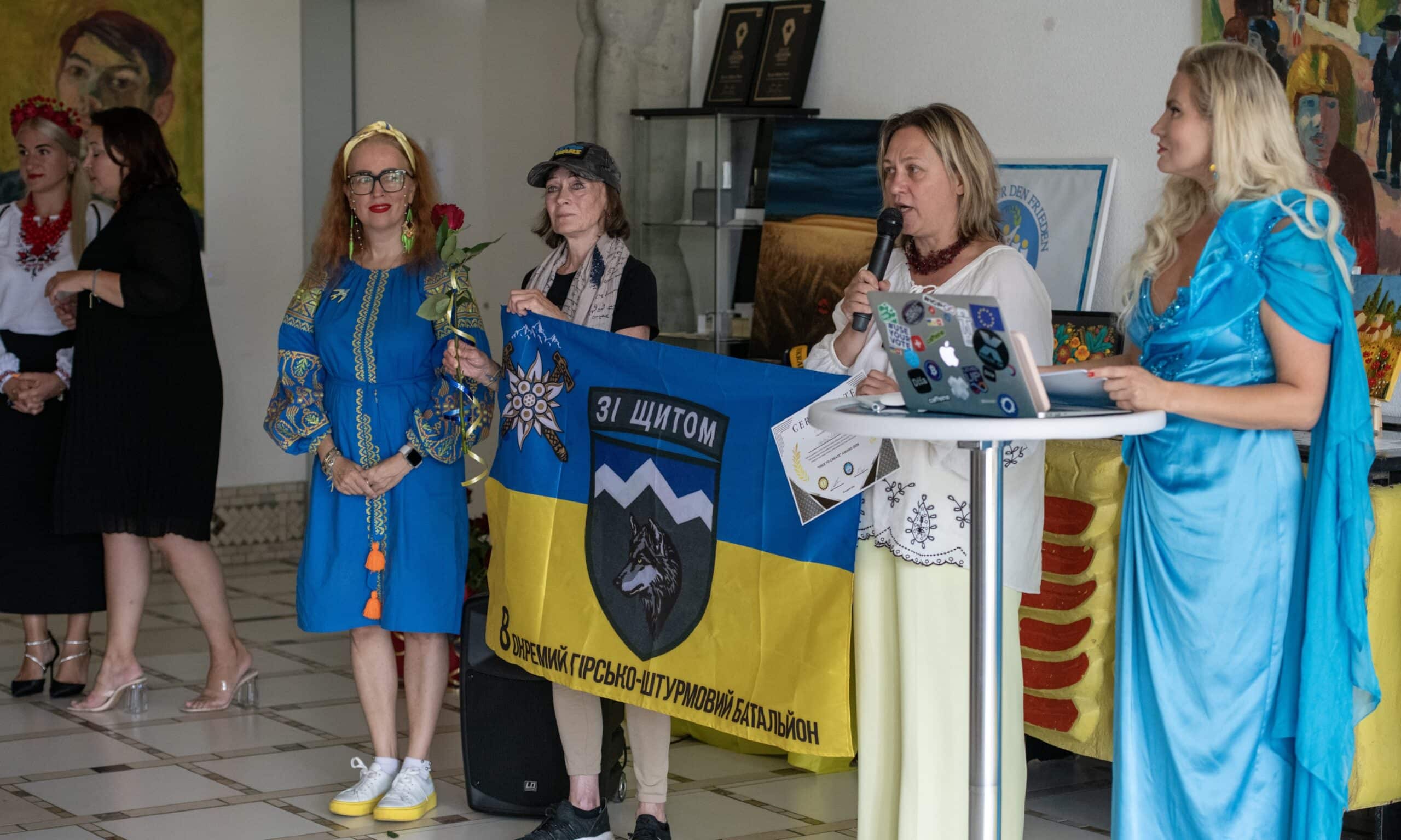Ведучі – Олеся Тарасенко і володарка титулу Mrs Ukraine World International Маріанна Кох-Зорова – в синіх вбраннях. Церемонія «Вільні створювати» з нагоди Дня Незалежності України. Парк Бруно Вебера в Дітіконі, Швейцарія. 23 серпня 2025 р. (© Samuel Etzensperger / Herz2Herz)