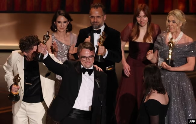 Павел Таланкин с режиссером Дэвидом Боренштейном и продюсерами фильма на церемонии вручения «Оскара», 15 марта 2026 г. (© AFP)
